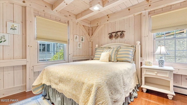 bedroom with wood walls, wood finished floors, multiple windows, and beamed ceiling