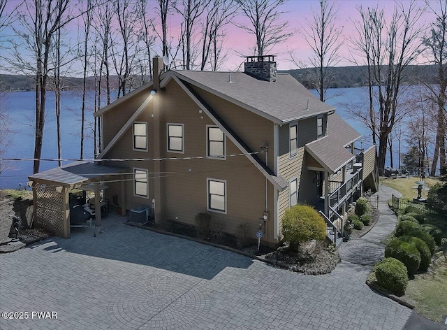 exterior space featuring a water view, central AC unit, and a chimney