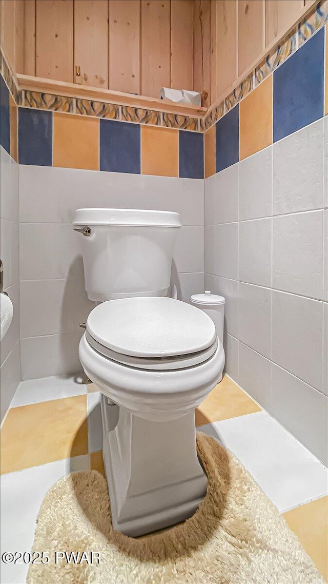 bathroom with toilet and tile walls