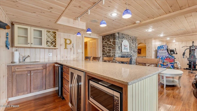 kitchen with a peninsula, stainless steel microwave, wood finished floors, and wooden ceiling