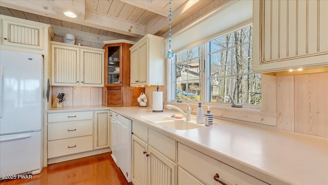 kitchen with beam ceiling, a sink, wooden ceiling, light countertops, and white appliances