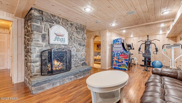 living area with wooden walls, wood ceiling, arched walkways, and wood finished floors
