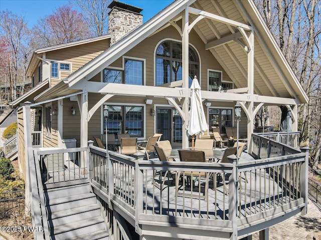 rear view of property with covered porch, a chimney, and outdoor dining space