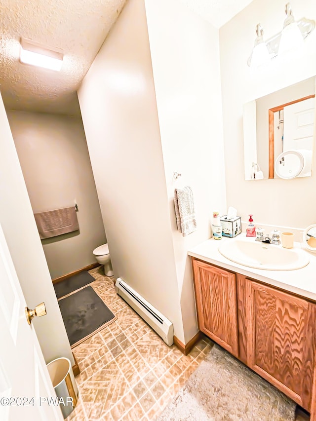 bathroom with a baseboard radiator, tile patterned flooring, a textured ceiling, toilet, and vanity