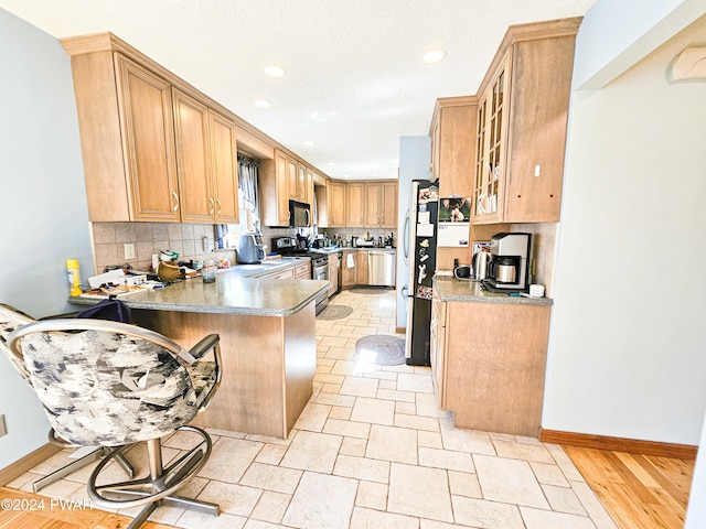 kitchen with a kitchen bar, kitchen peninsula, decorative backsplash, and appliances with stainless steel finishes