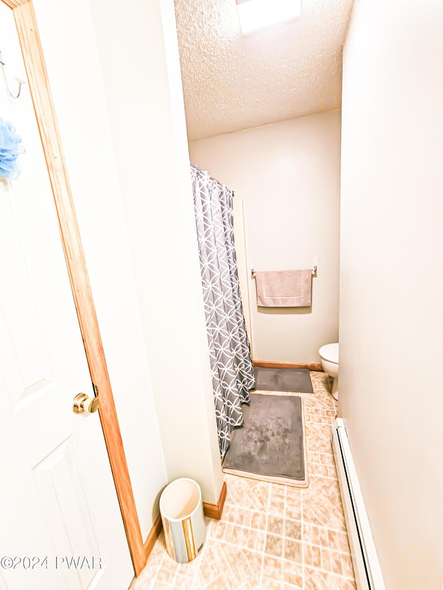 bathroom featuring a baseboard radiator, a shower with curtain, a wall mounted AC, a textured ceiling, and toilet