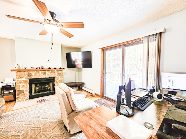 home office featuring baseboard heating, a fireplace, light hardwood / wood-style floors, and a textured ceiling