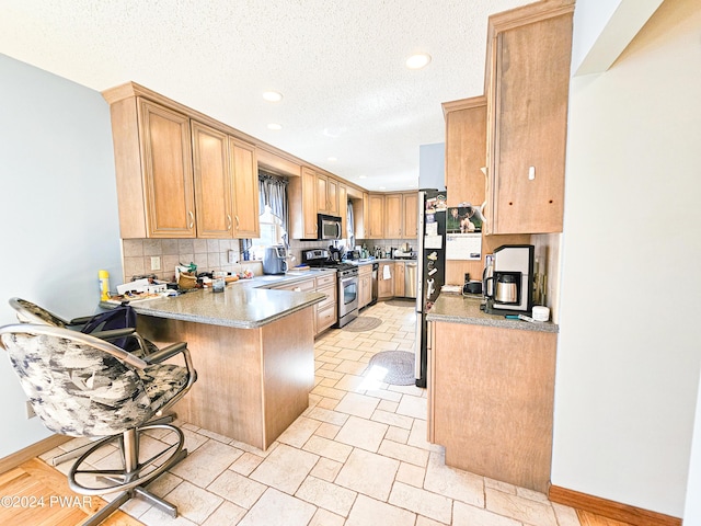 kitchen featuring a kitchen breakfast bar, decorative backsplash, a textured ceiling, kitchen peninsula, and stainless steel appliances