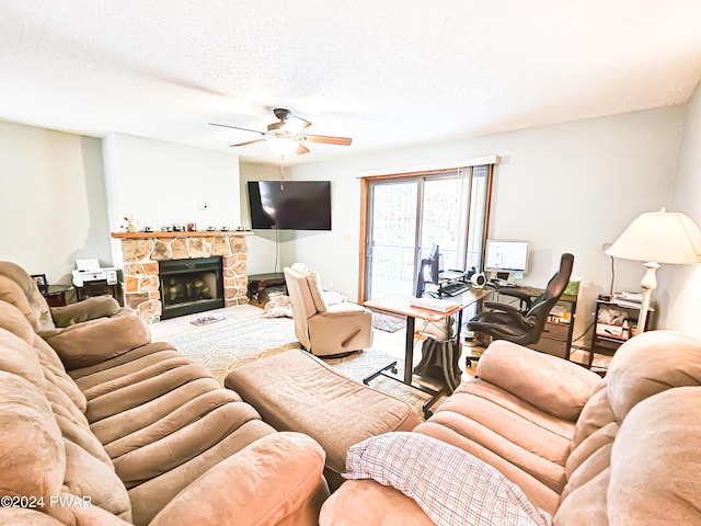 living room featuring ceiling fan, a fireplace, and a textured ceiling