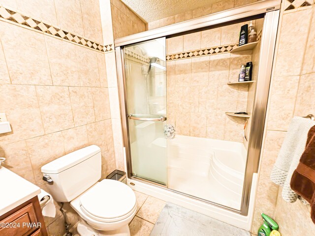 bathroom with vanity, an enclosed shower, tile walls, and toilet