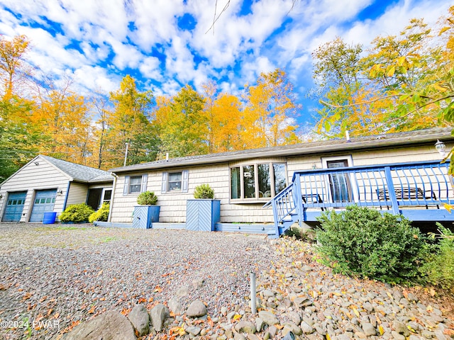 single story home featuring an outbuilding, a garage, and a deck