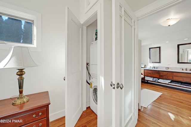 corridor with sink, light hardwood / wood-style floors, and stacked washer / drying machine