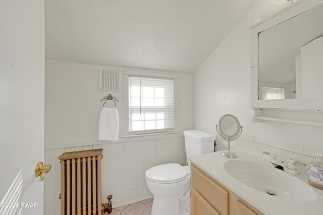 bathroom featuring radiator heating unit, tile patterned flooring, vaulted ceiling, toilet, and vanity