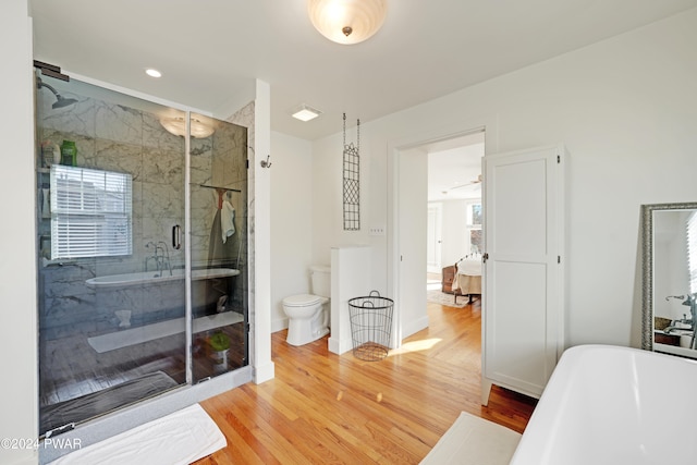 bathroom with a wealth of natural light, toilet, independent shower and bath, and hardwood / wood-style flooring