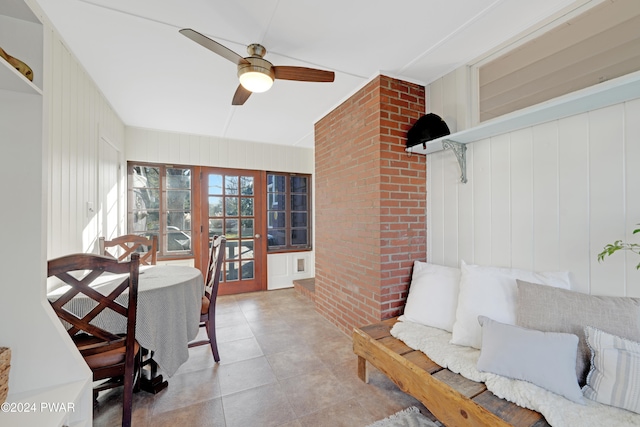 interior space with ceiling fan and wood walls