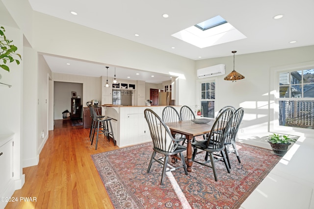 dining area with light wood-type flooring, a wall mounted AC, and a skylight