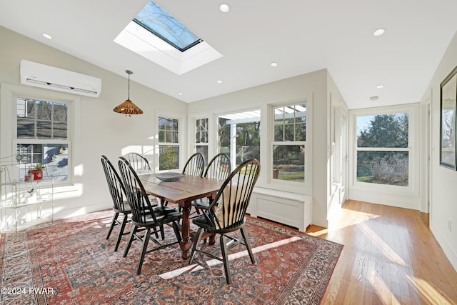 dining room featuring light wood-type flooring, a wall mounted AC, and vaulted ceiling with skylight