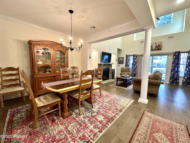 dining space with decorative columns, crown molding, visible vents, and dark wood-type flooring