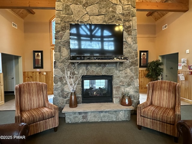 living area featuring visible vents, high vaulted ceiling, a fireplace, and beam ceiling