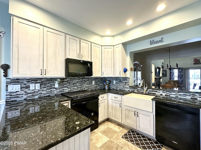 kitchen featuring a sink, black appliances, tasteful backsplash, dark stone countertops, and decorative light fixtures