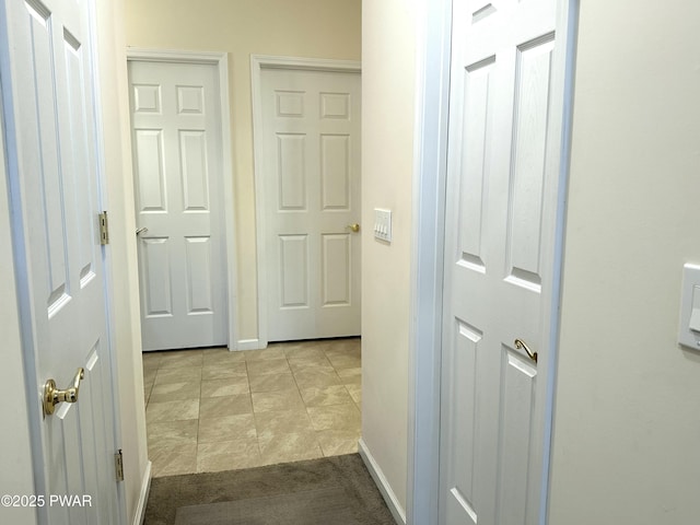 corridor with light tile patterned floors and baseboards