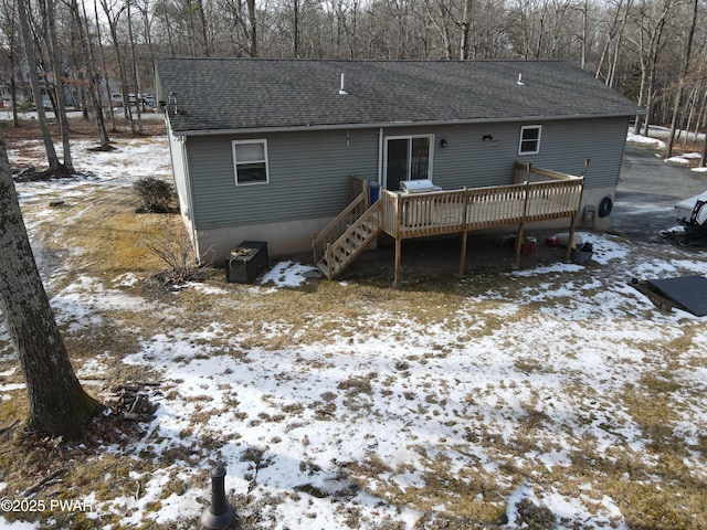 snow covered back of property with a wooden deck