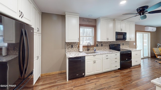 kitchen with sink, tasteful backsplash, a wall mounted air conditioner, black appliances, and white cabinets