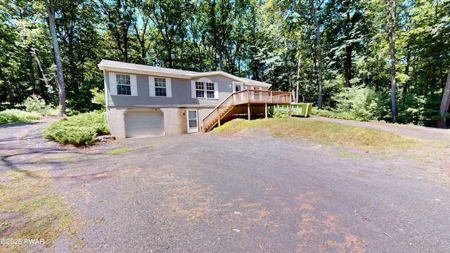 103 Windwards Ln, Dingmans Ferry, PA 18328 - view of front facade featuring stairway, dirt driveway, an attached garage, a wooden deck, and view of scattered trees