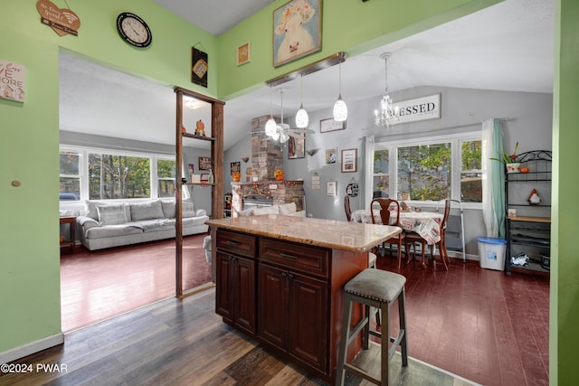 kitchen featuring dark hardwood / wood-style flooring, a breakfast bar, pendant lighting, a kitchen island, and lofted ceiling