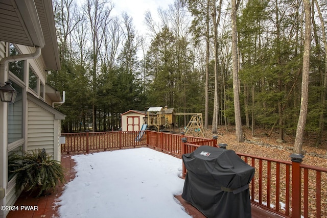 deck with a playground, grilling area, and a storage shed