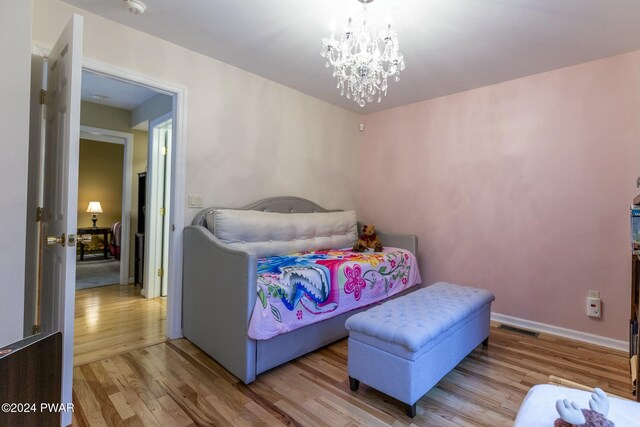 bedroom with light hardwood / wood-style flooring and a notable chandelier