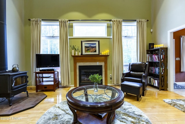 sitting room with a wood stove, a high ceiling, and light wood-type flooring