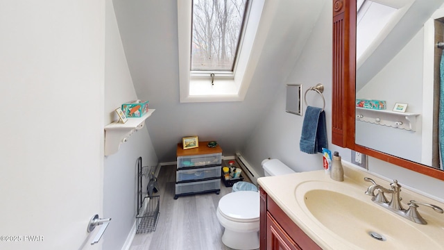 bathroom featuring toilet, a skylight, wood finished floors, and vanity