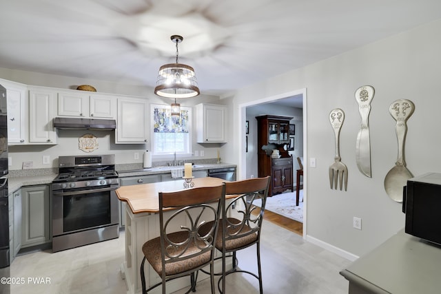 102 Circle Dr, Milford, PA 18337 - kitchen with gas range, under cabinet range hood, a breakfast bar, white cabinetry, and decorative light fixtures