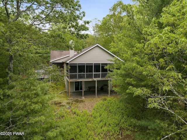 102 Circle Dr, Milford, PA 18337 - rear view of house featuring a sunroom, a chimney, and a forest view