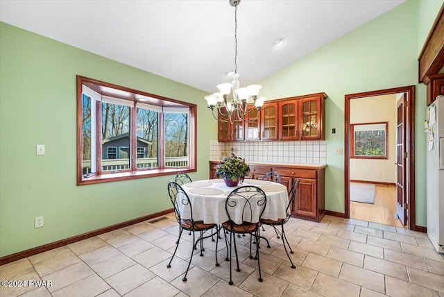 dining area with a notable chandelier, light tile patterned floors, a wealth of natural light, and vaulted ceiling