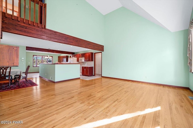 unfurnished living room featuring high vaulted ceiling and light hardwood / wood-style flooring