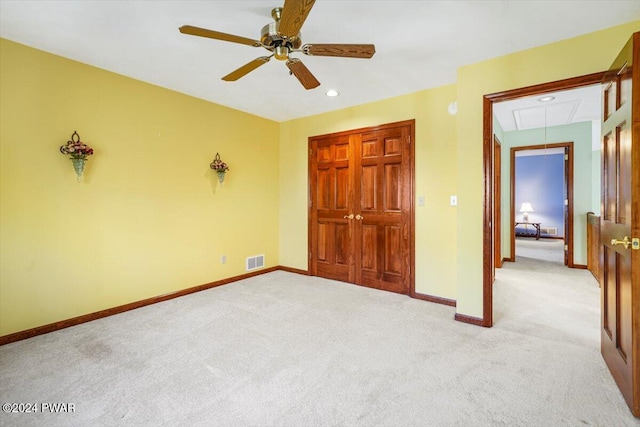 unfurnished bedroom featuring ceiling fan, a closet, and light carpet