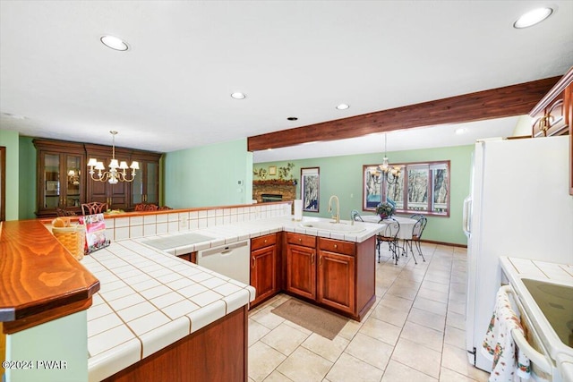 kitchen featuring kitchen peninsula, beam ceiling, an inviting chandelier, tile counters, and hanging light fixtures