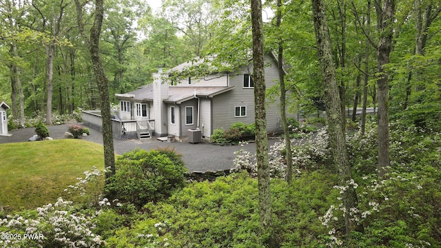 147 Goldrush Dr, Lords Valley, PA 18428 - view of front of property featuring a chimney, a forest view, a deck, a front lawn, and asphalt driveway