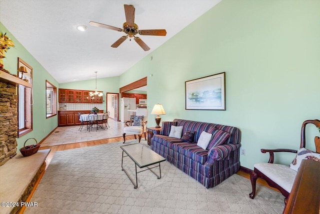 living room with ceiling fan with notable chandelier, lofted ceiling, and light hardwood / wood-style flooring