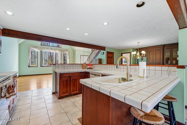 kitchen featuring sink, hanging light fixtures, backsplash, kitchen peninsula, and light tile patterned floors