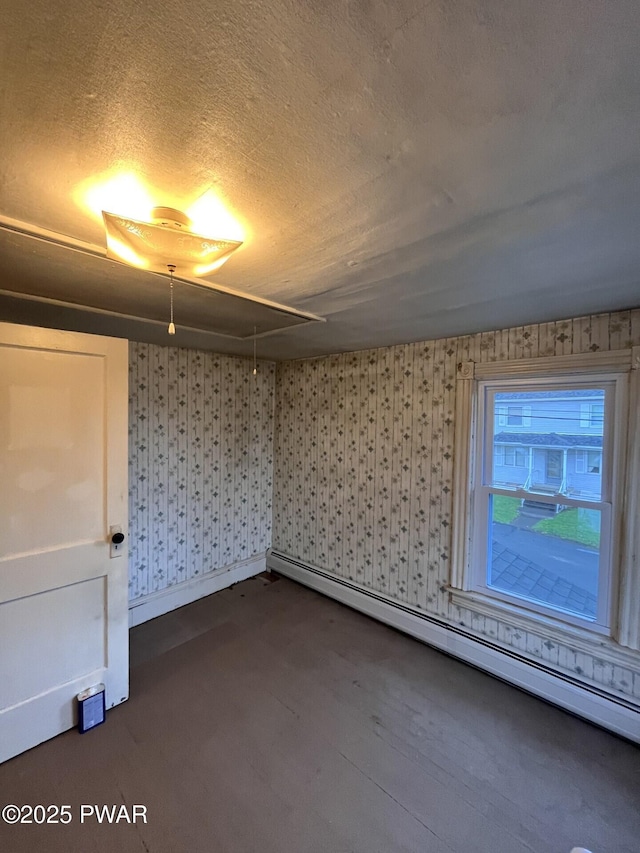 interior space featuring wallpapered walls, a textured ceiling, baseboards, and a baseboard heating unit