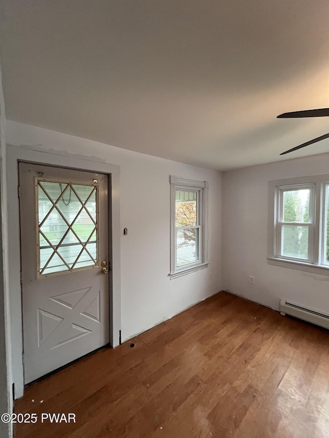 entryway featuring a ceiling fan, a wealth of natural light, a baseboard radiator, and wood finished floors