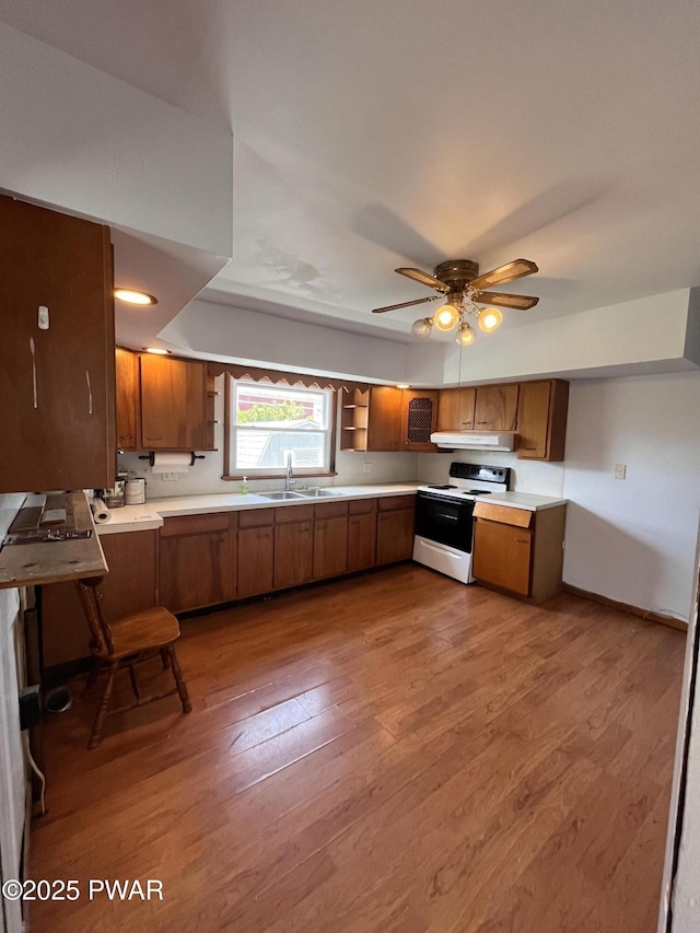 109 N St, Forest City, PA 18421 - kitchen with white electric range, brown cabinets, wood finished floors, under cabinet range hood, and light countertops