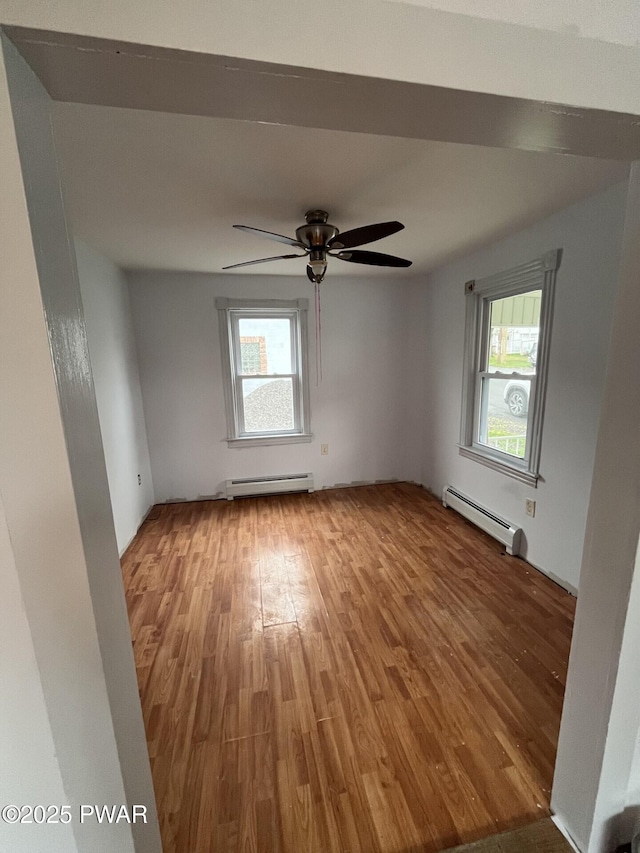 spare room featuring plenty of natural light, baseboard heating, and wood finished floors