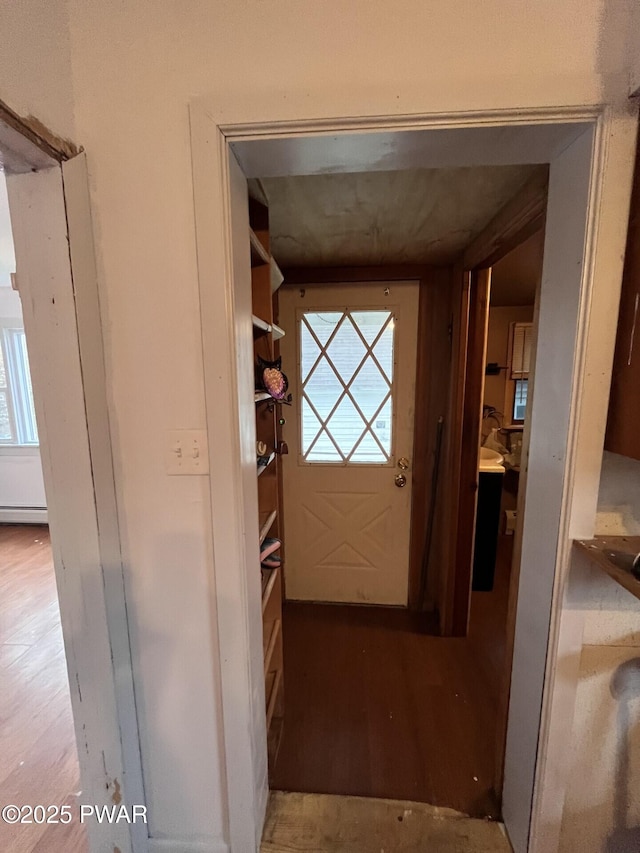 doorway to outside with baseboard heating and wood finished floors