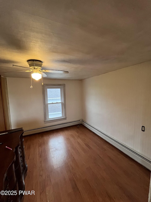 empty room featuring wood finished floors, baseboard heating, and ceiling fan