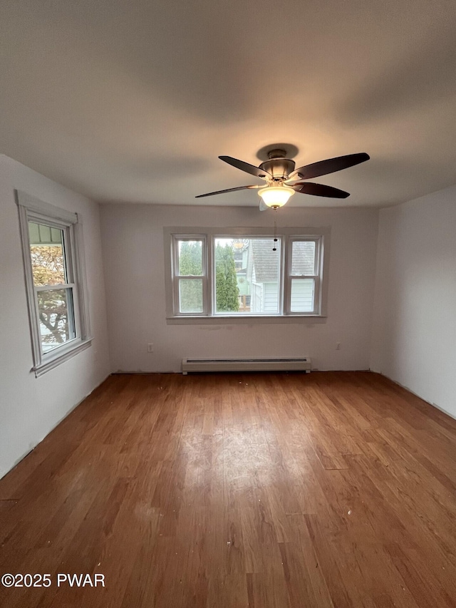 spare room featuring baseboard heating, ceiling fan, and wood finished floors