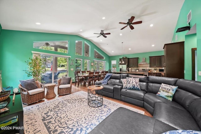 living room with hardwood / wood-style floors, ceiling fan, and high vaulted ceiling